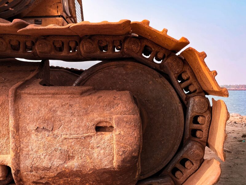 Detailed view of an excavator on sandy terrain by Alappuzha's shore, showcasing engineering strength.